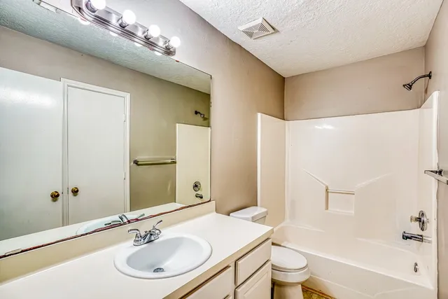a bathroom with a sink a toilet a mirror and shower