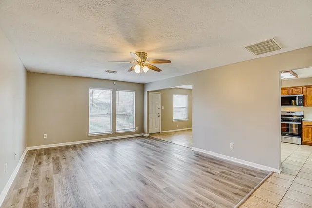 a view of an empty room with window and wooden floor