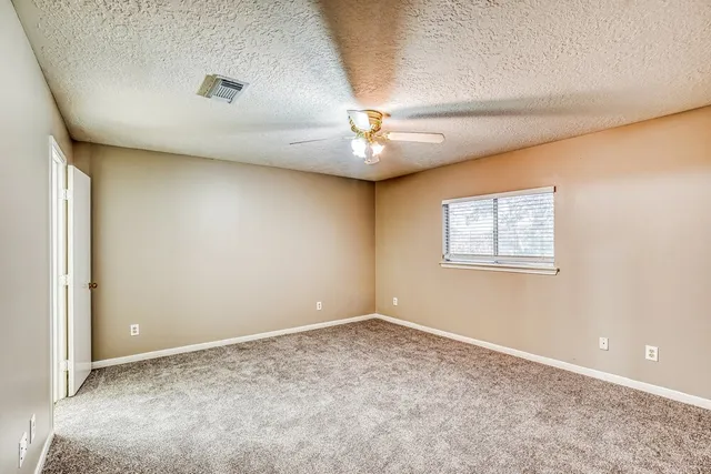 an empty room with a ceiling fan and a window
