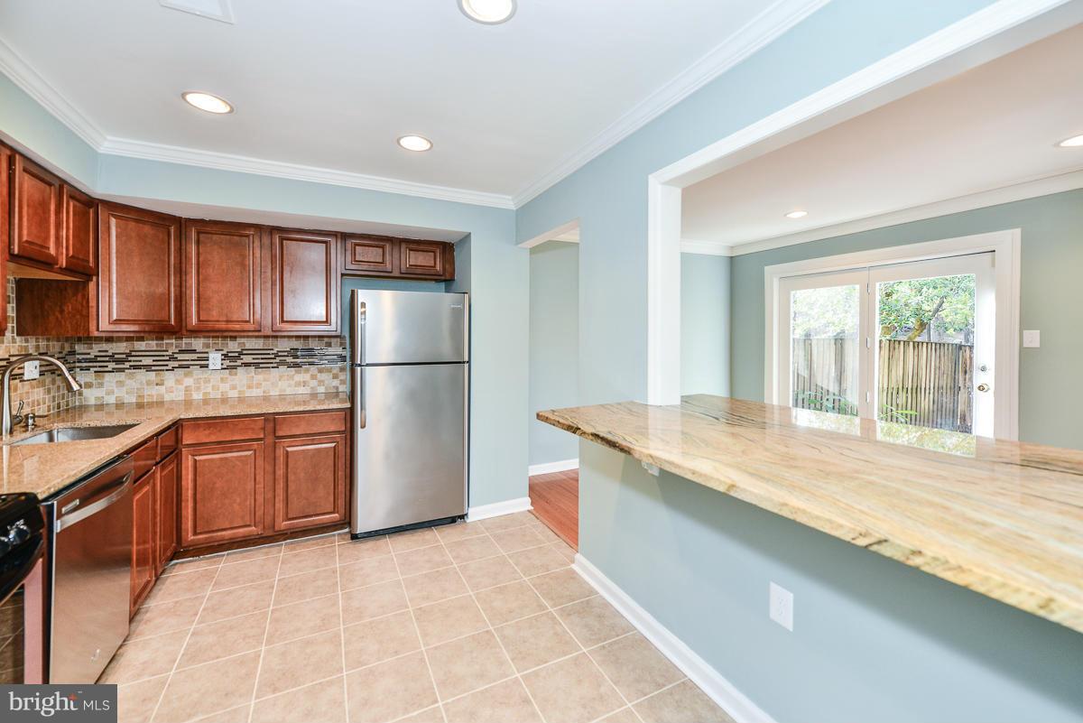 2407 Alsop Court Reston, VA 20191 - Photo 7 of 30 a kitchen with stainless steel appliances granite countertop a refrigerator a sink dishwasher a stove with wooden cabinets and floor