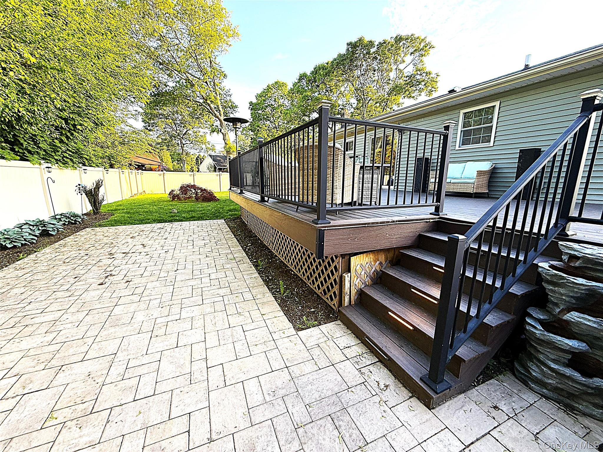 1 Heston Road Shirley, NY 11967 - Photo 26 of 32 Expansive patterned patio with a wood-finish deck featuring dark railings
