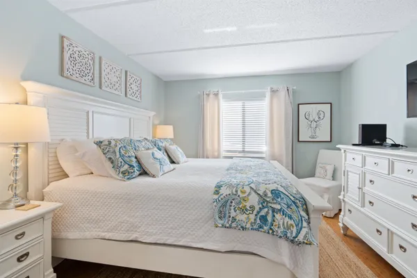 a bedroom with a large bed and a flat tv screen on dresser