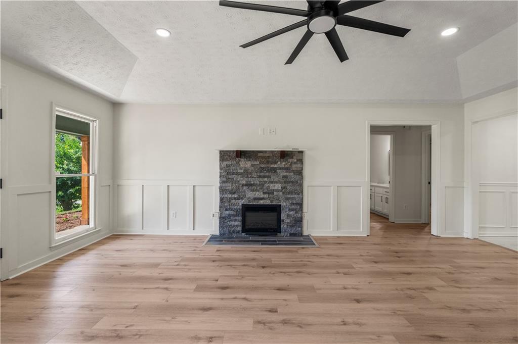 766 Lee Road Phenix City, AL 36870 - Photo 4 of 30 Unfurnished living room with ceiling fan, a decorative wall, light wood-type flooring, lofted ceiling, and a textured ceiling
