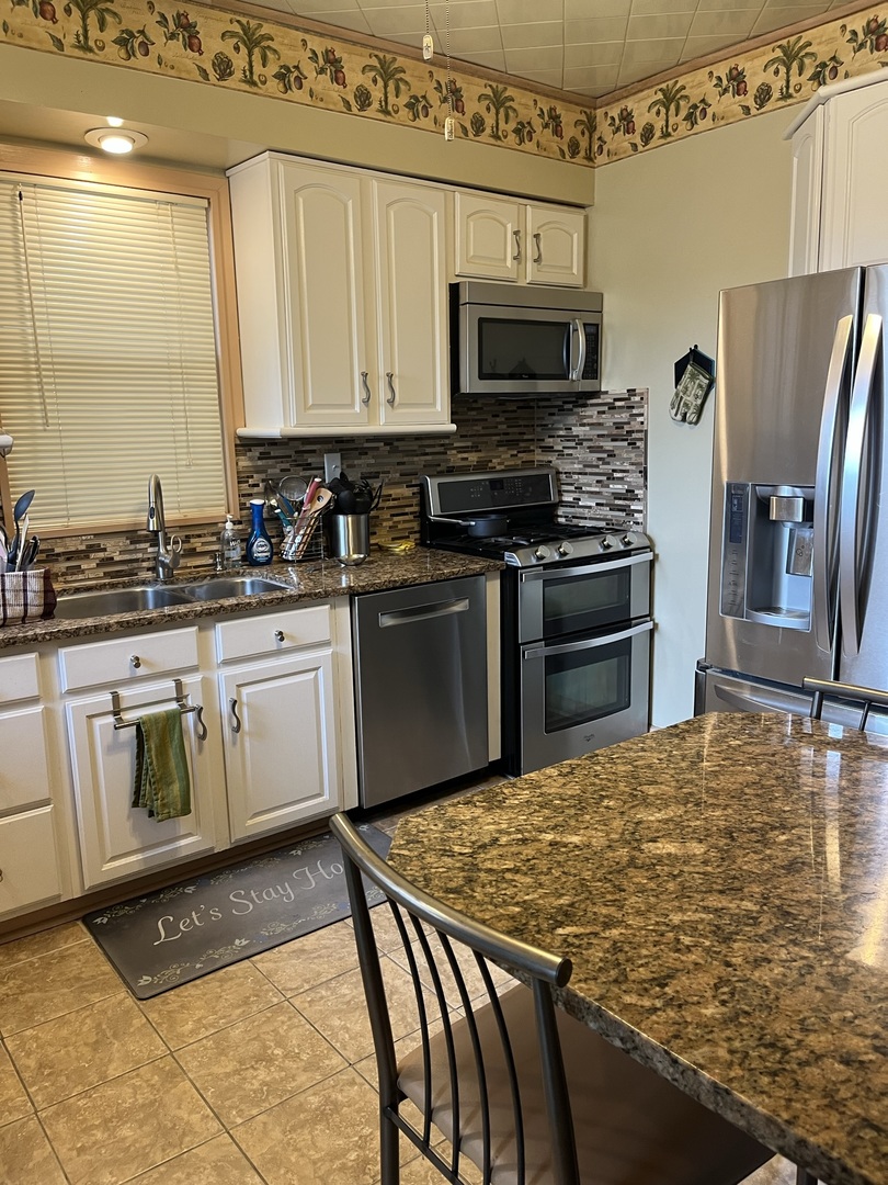 1855 East 81st Street Chicago, IL 60617 - Photo 3 of 3 a kitchen with stainless steel appliances granite countertop a stove top oven a sink a dining table and chairs