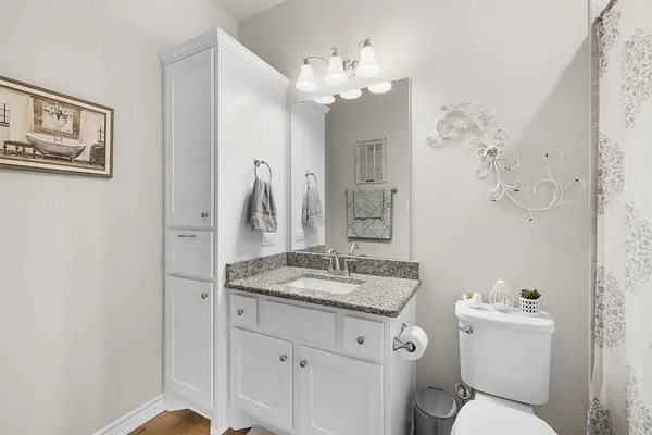 a bathroom with a granite countertop sink mirror vanity and toilet
