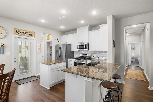 a kitchen with stainless steel appliances granite countertop a refrigerator and a stove top oven