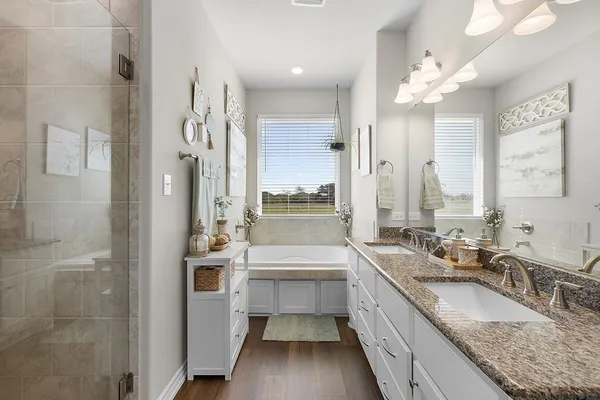 a bathroom with a granite countertop double vanity sink a mirror and a bathtub