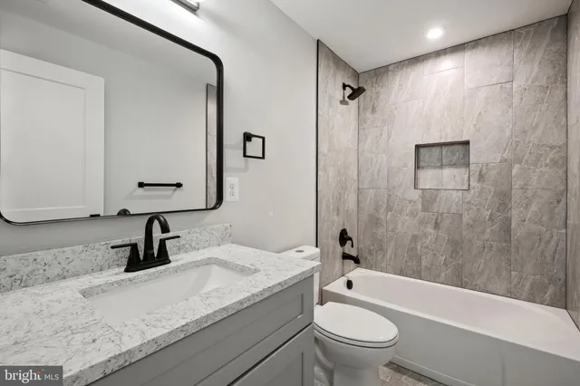 a bathroom with a granite countertop sink a toilet and a mirror