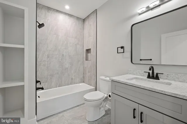 a bathroom with a granite countertop toilet a sink and a bathtub