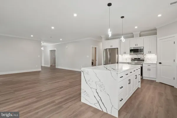 a kitchen with stainless steel appliances kitchen island granite countertop a refrigerator a stove a oven and a cabinets with wooden floor