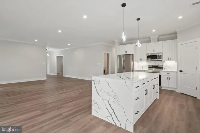 a kitchen with stainless steel appliances kitchen island granite countertop a refrigerator a stove a oven and a cabinets with wooden floor