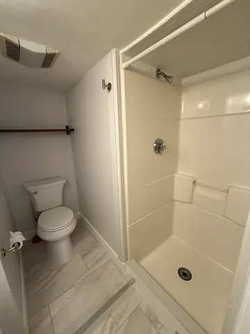 a bathroom with a granite countertop shower a toilet and a shower