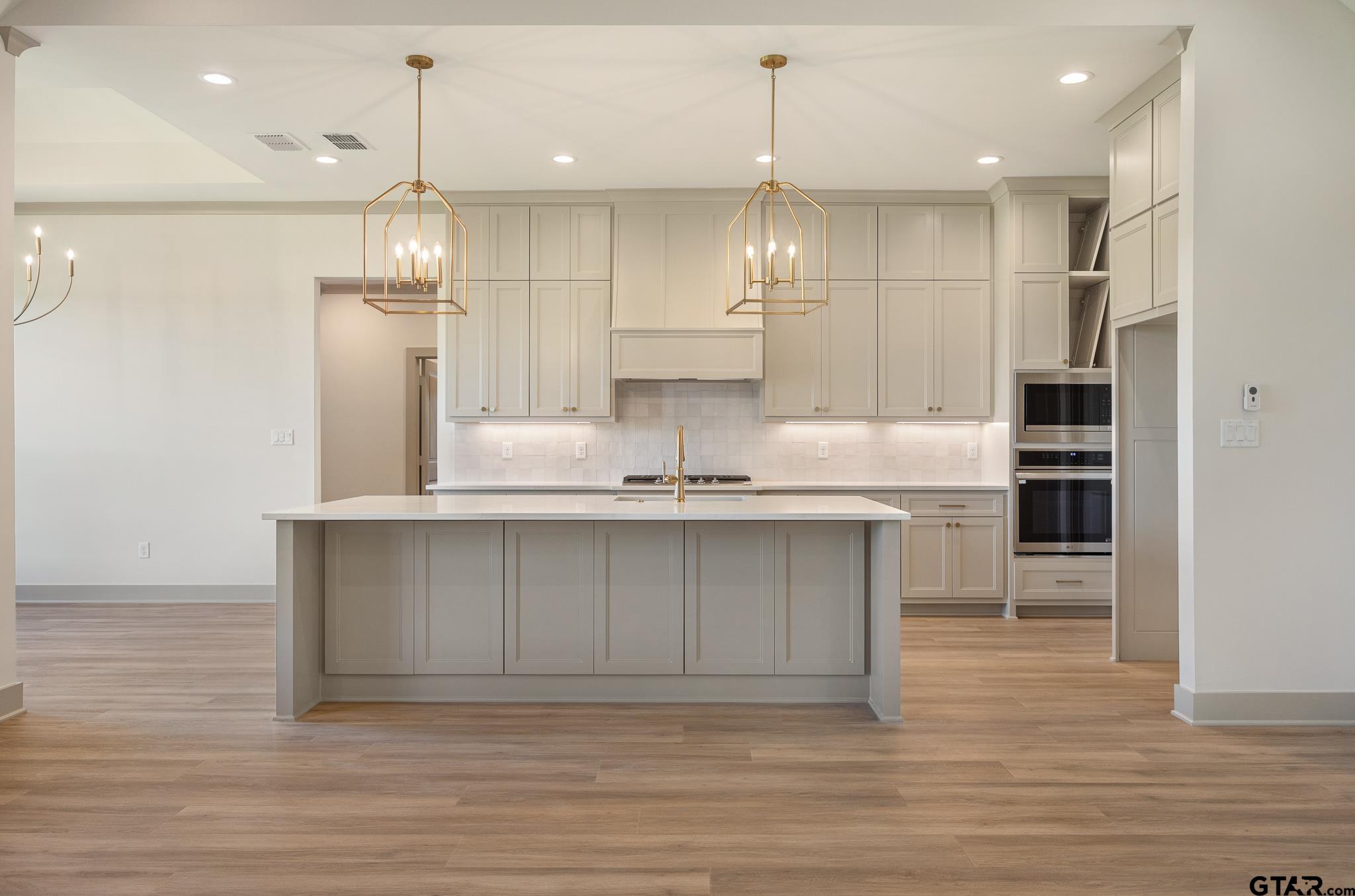 508 Artesian Meadow Drive Bullard, TX 75757 - Photo 13 of 46 a large kitchen with stainless steel appliances kitchen island a refrigerator and a wooden floors