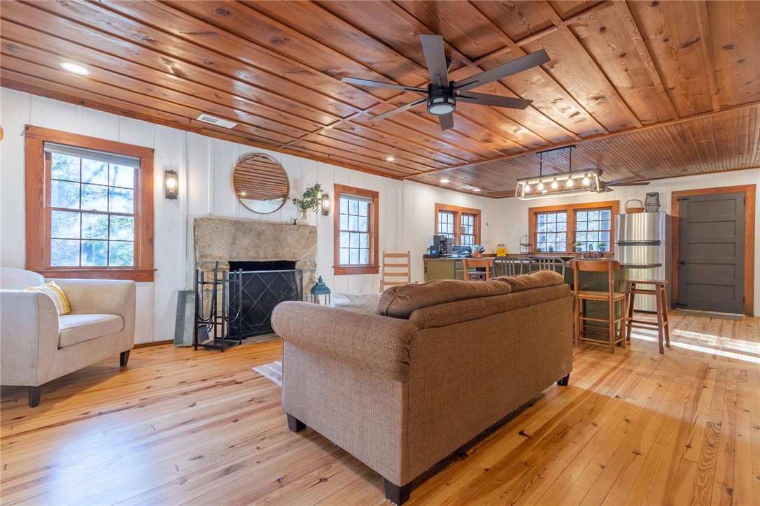 205 Rocky Bottom Road Sunset, SC 29685 - Photo 7 of 46 Rich wood plank ceilings and matching floors anchor this open-concept living area with a stone fireplace.
