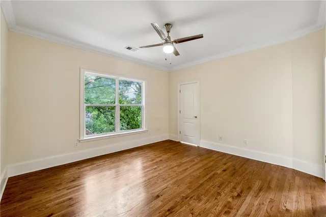 an empty room with wooden floor chandelier fan and windows