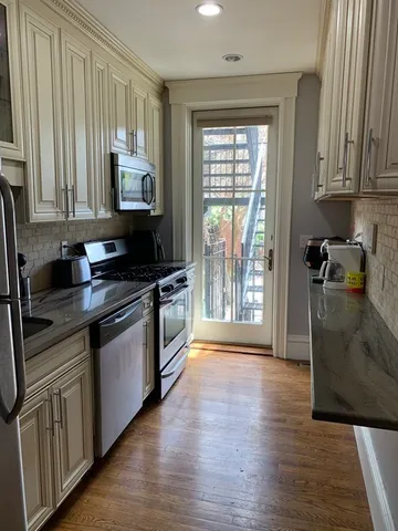 a kitchen with granite countertop a stove a sink a refrigerator and wooden floor