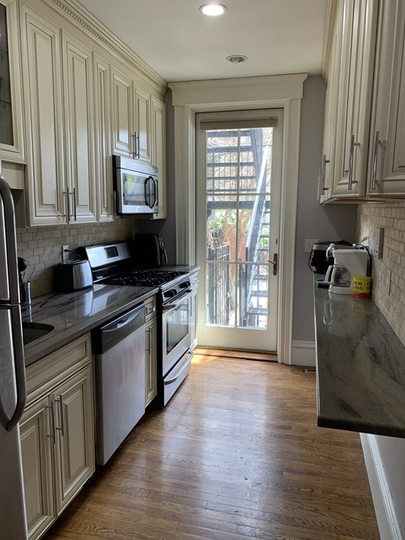 1 Wigglesworth Street, Unit 1 Boston, MA 02120 - Photo 4 of 39 a kitchen with granite countertop a stove a sink a refrigerator and wooden floor