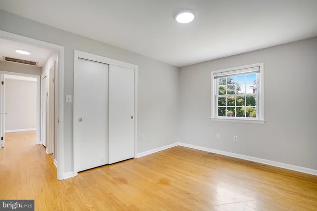 a view of empty room with window and wooden floor