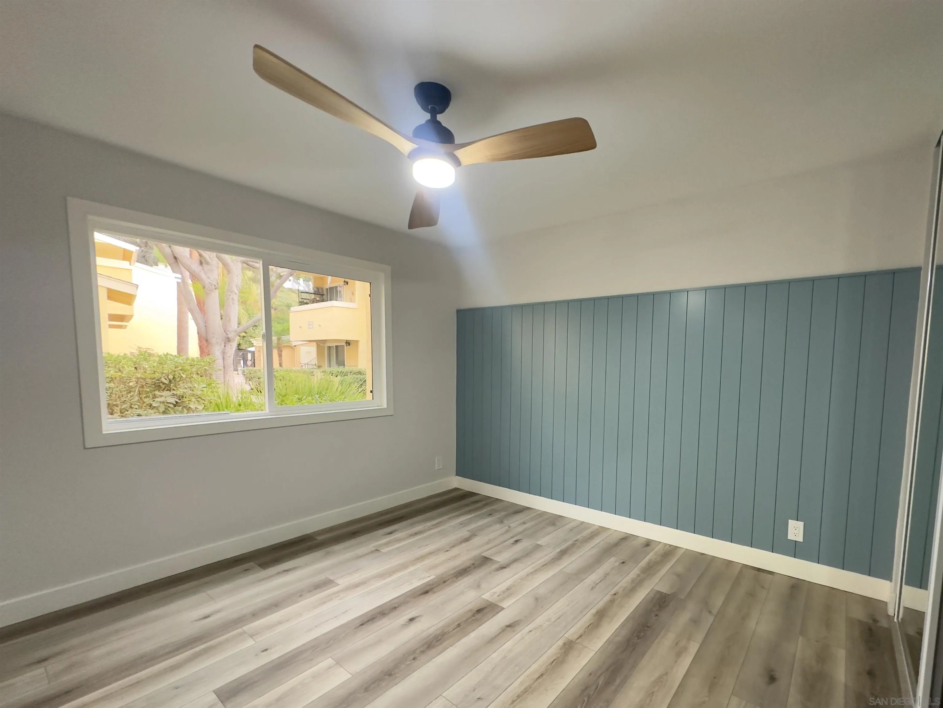 9929 Erma Road, Unit 102 San Diego, CA 92131 - Photo 14 of 14 a view of an empty room with wooden floor and a window