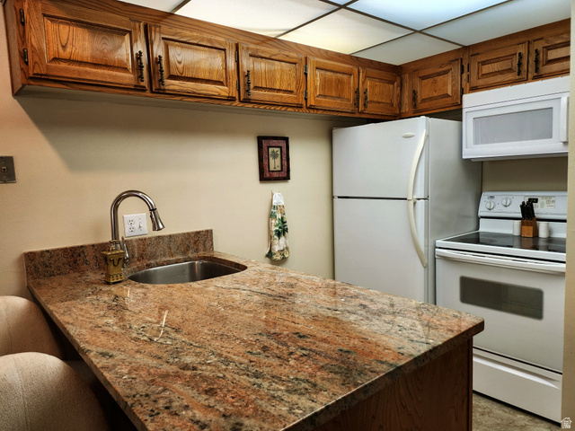 860 South Village Road, Unit Z10 St. George, UT 84770 - Photo 2 of 18 Kitchen featuring white appliances, light stone countertops, wood finish cabinets, and a peninsula