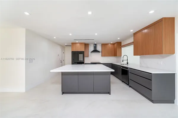 a large kitchen with stainless steel appliances a large counter top a stove and a refrigerator