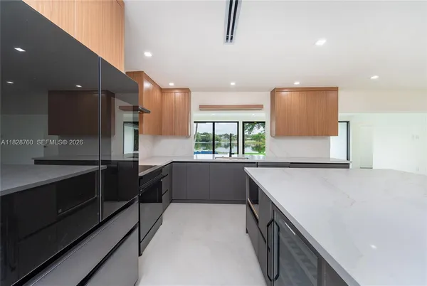 a large kitchen with stainless steel appliances a large counter top a stove and a refrigerator