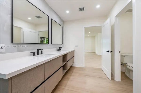 a large white bathroom with a double vanity sink a mirror and a bathtub