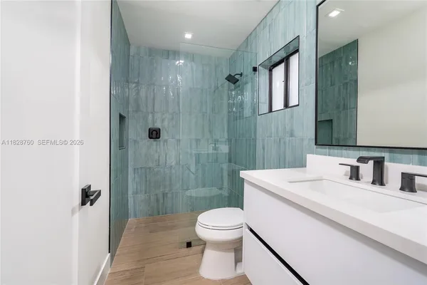 a bathroom with a toilet a sink a mirror a vanity and shower