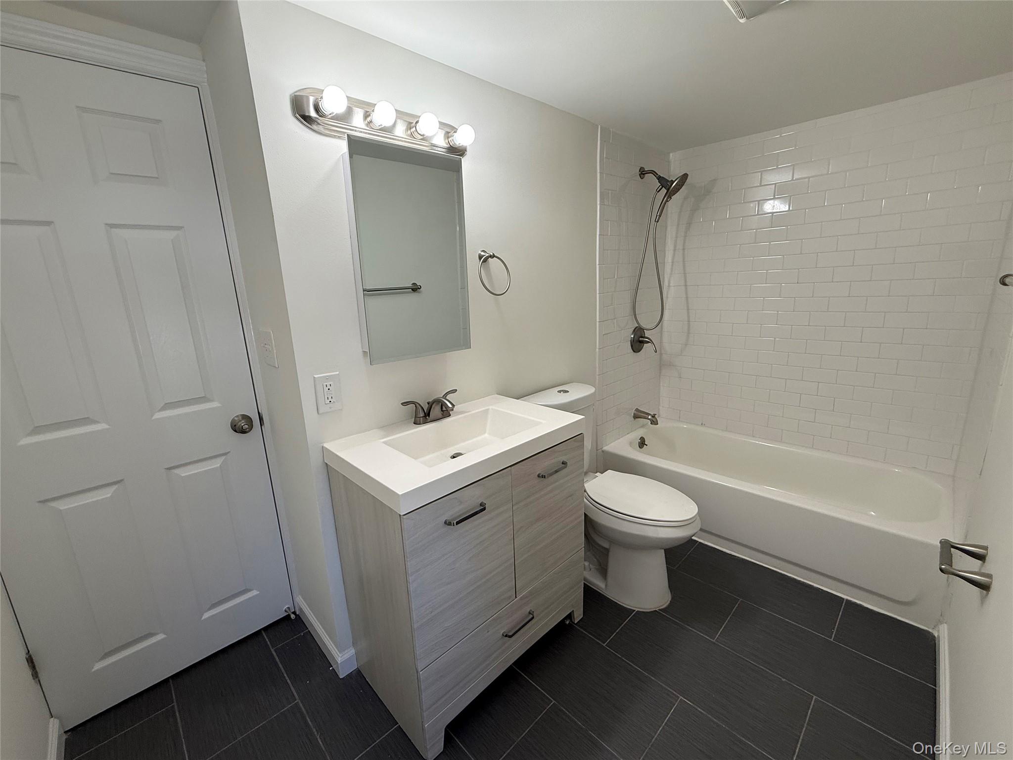225 Fir Grove Road Ronkonkoma, NY 11779 - Photo 19 of 22 a bathroom with a toilet sink and mirror with bathtub