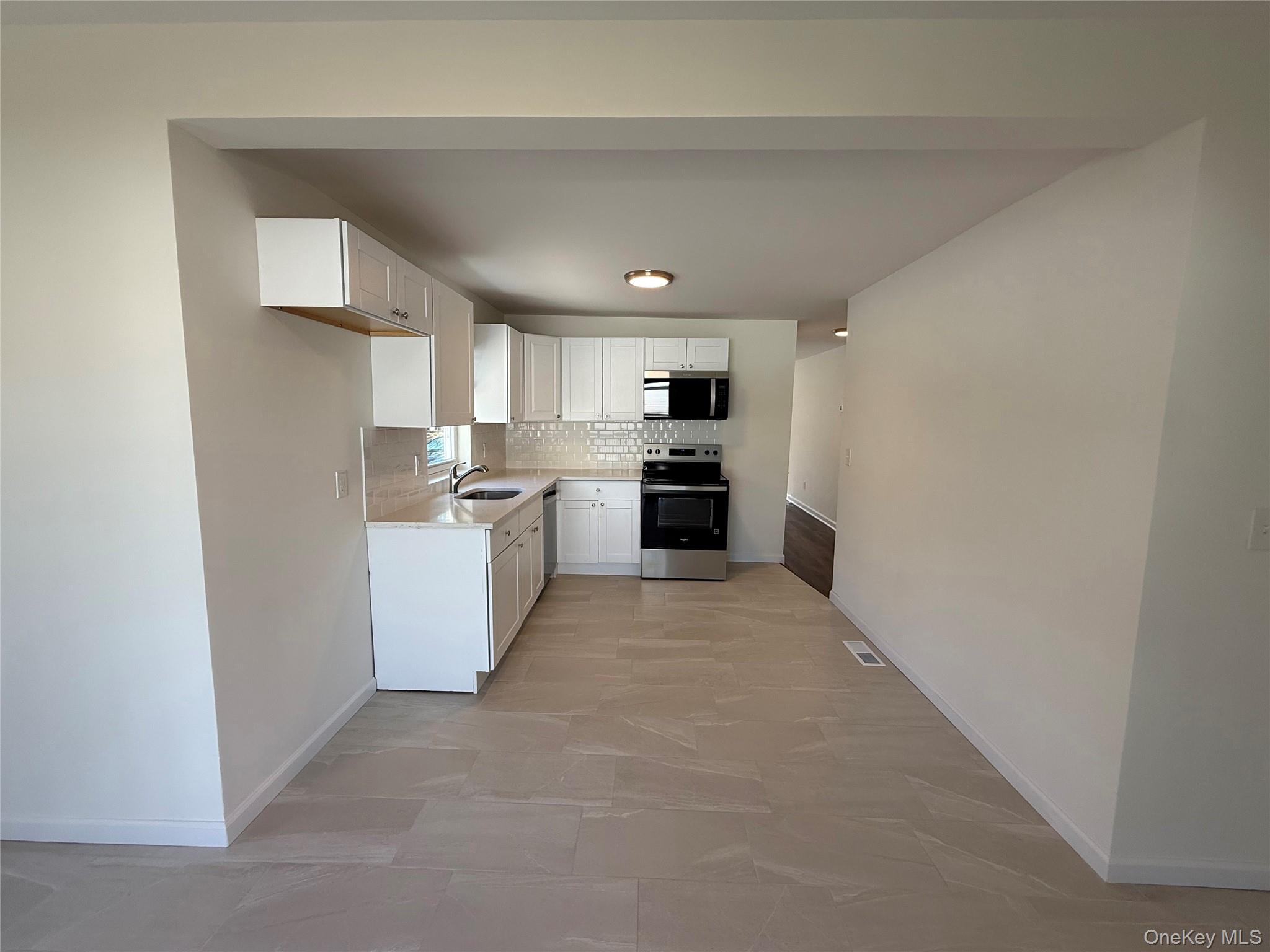 225 Fir Grove Road Ronkonkoma, NY 11779 - Photo 6 of 22 a kitchen with refrigerator and cabinets