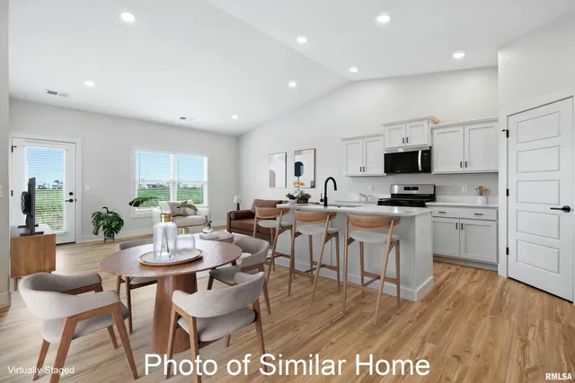 a large kitchen with stainless steel appliances a large counter top a stove a sink cabinets and a wooden floor