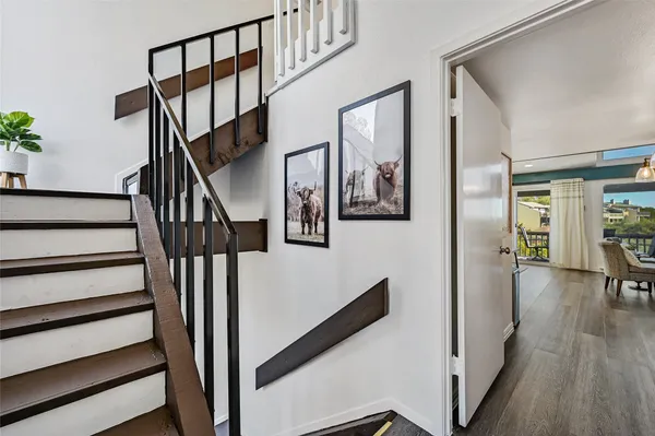 a view of staircase with lots of frames on wall and wooden floor