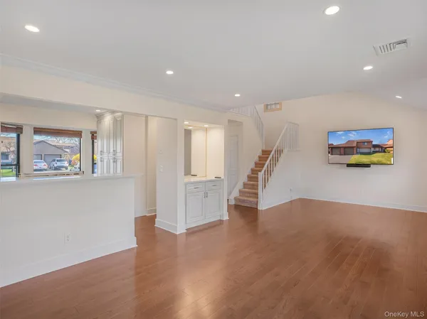 a view of empty room with wooden floor and white walls