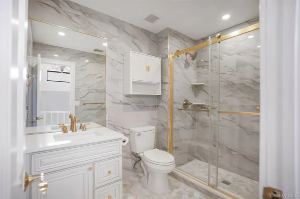 a bathroom with a shower sink vanity mirror and toilet