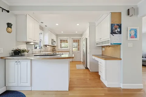 a kitchen with white cabinets and sink