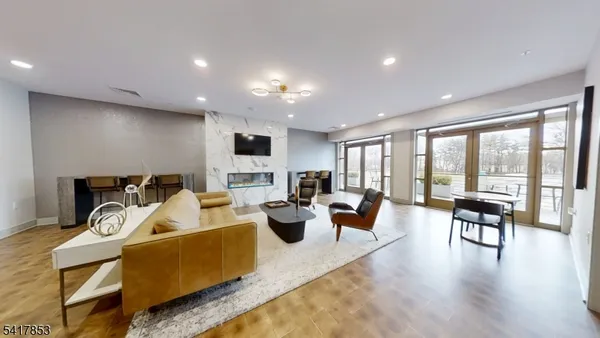 a living room with furniture a large window and wooden floor