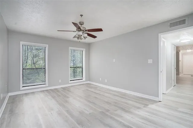 a view of an empty room with a window and wooden floor