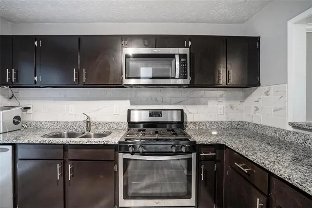 a kitchen with granite countertop a sink and a stove