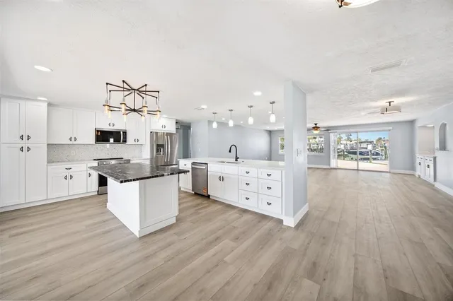 a kitchen with stainless steel appliances kitchen island wooden floors and white cabinets