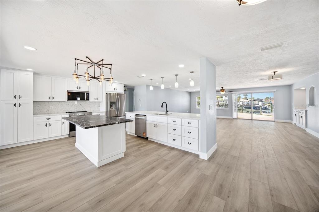 6410 3rd Palm Point St. Pete Beach, FL 33706 - Photo 1 of 54 a kitchen with stainless steel appliances kitchen island wooden floors and white cabinets