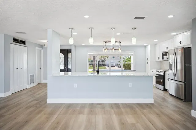 a large kitchen with stainless steel appliances kitchen island a large counter top and wooden floors