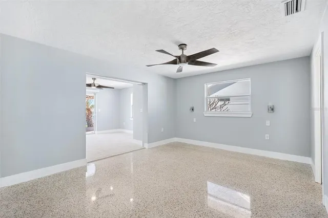 an empty room with a ceiling fan and carpet