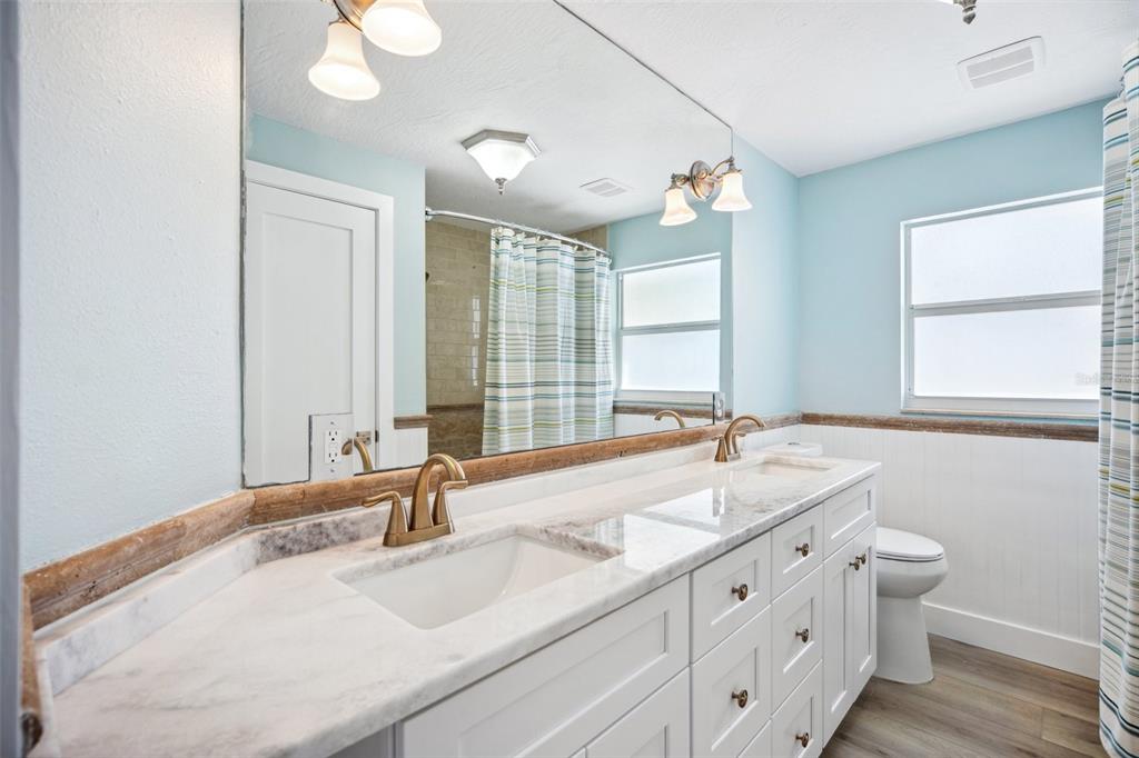 6410 3rd Palm Point St. Pete Beach, FL 33706 - Photo 36 of 54 a bathroom with double vanity sinks a large mirror and a window