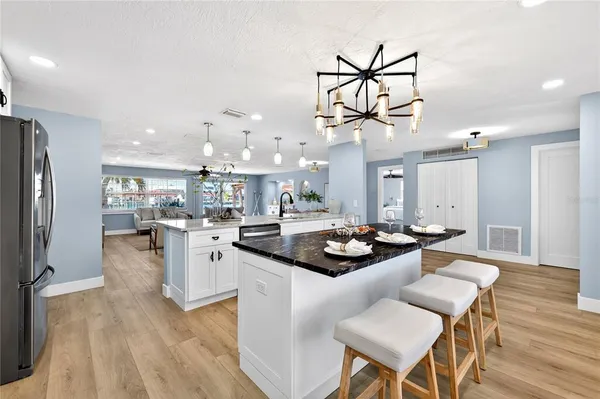a kitchen with stainless steel appliances a dining table chairs stove and refrigerator