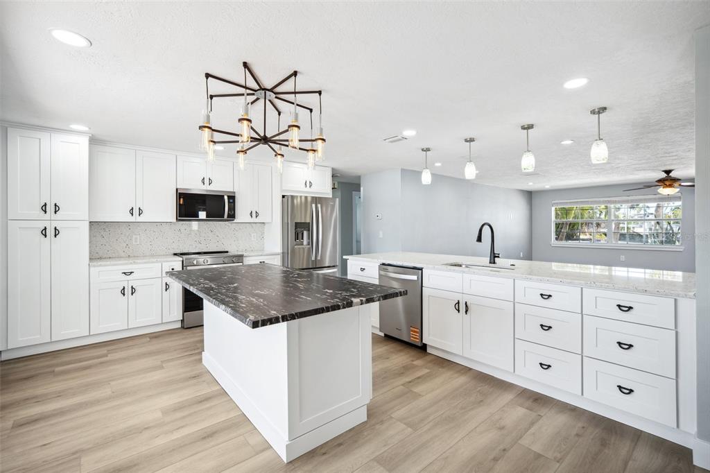 6410 3rd Palm Point St. Pete Beach, FL 33706 - Photo 5 of 54 a kitchen with granite countertop a sink cabinets stainless steel appliances and a center island