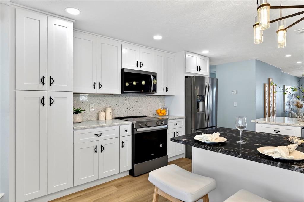 6410 3rd Palm Point St. Pete Beach, FL 33706 - Photo 57 of 71 a kitchen with white cabinets and stainless steel appliances