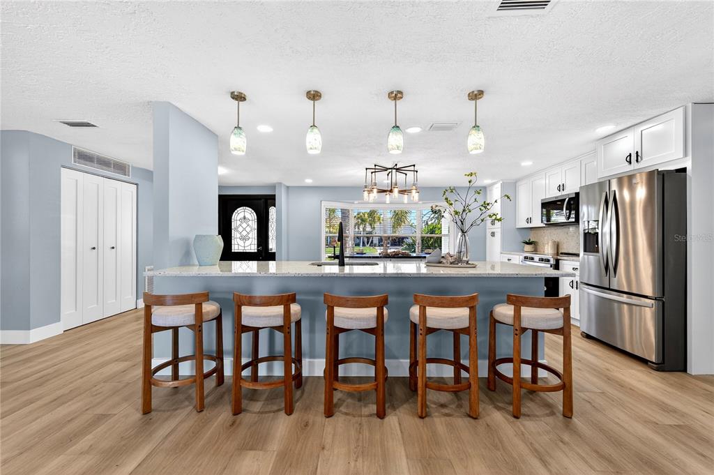6410 3rd Palm Point St. Pete Beach, FL 33706 - Photo 6 of 71 a kitchen with stainless steel appliances a dining table chairs stove and refrigerator
