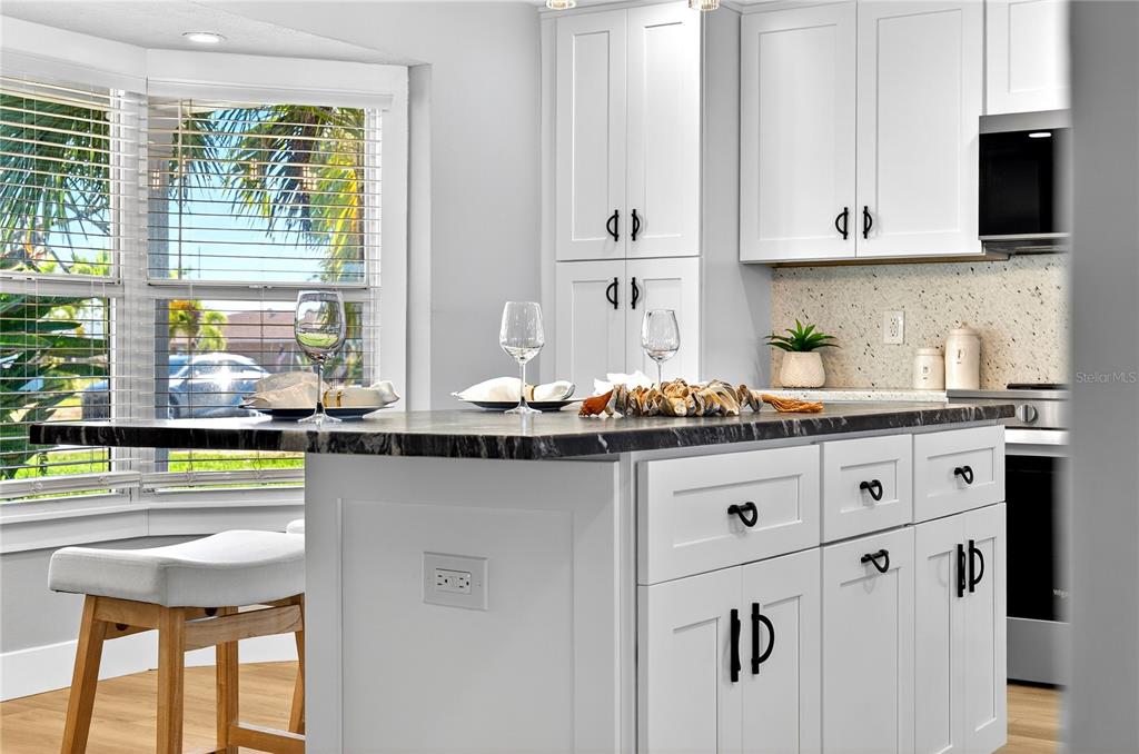 6410 3rd Palm Point St. Pete Beach, FL 33706 - Photo 65 of 71 a kitchen with stainless steel appliances granite countertop white cabinets and window
