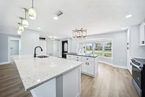 a view of a kitchen with kitchen island a sink stainless steel appliances and living room view