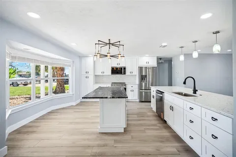 a large kitchen with stainless steel appliances kitchen island a large counter top and a wooden floors
